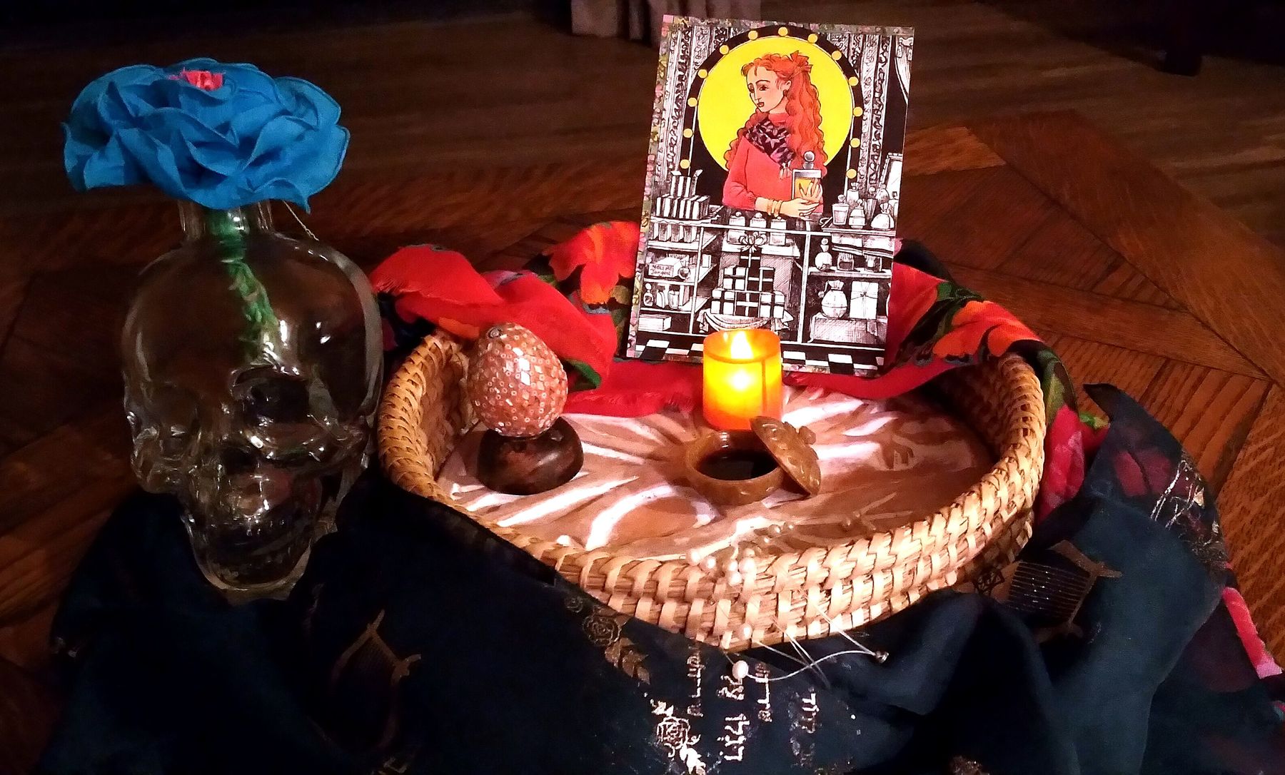 A healing ritual arrangement by Christine, with a lit candle, offerings and sacred objects on a woven tray